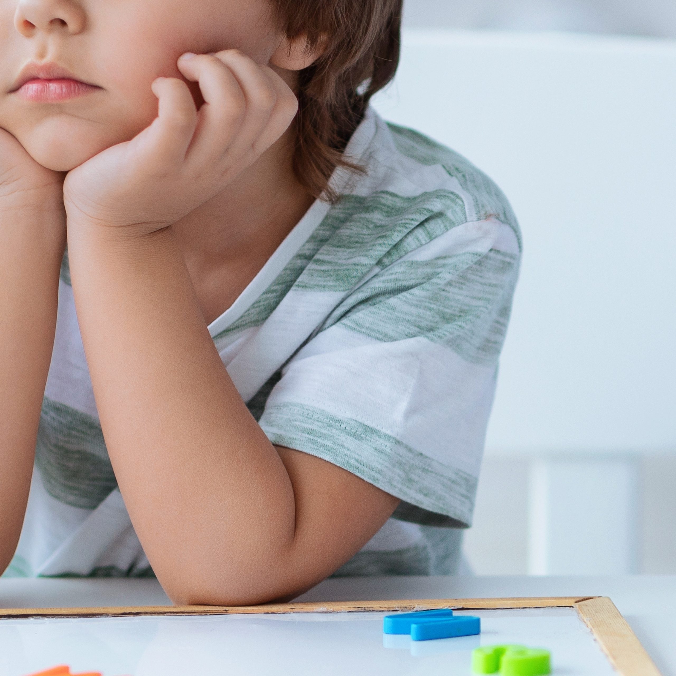 Child,Sits,At,Table,With,Learning,Tools,While,Adult,Engages