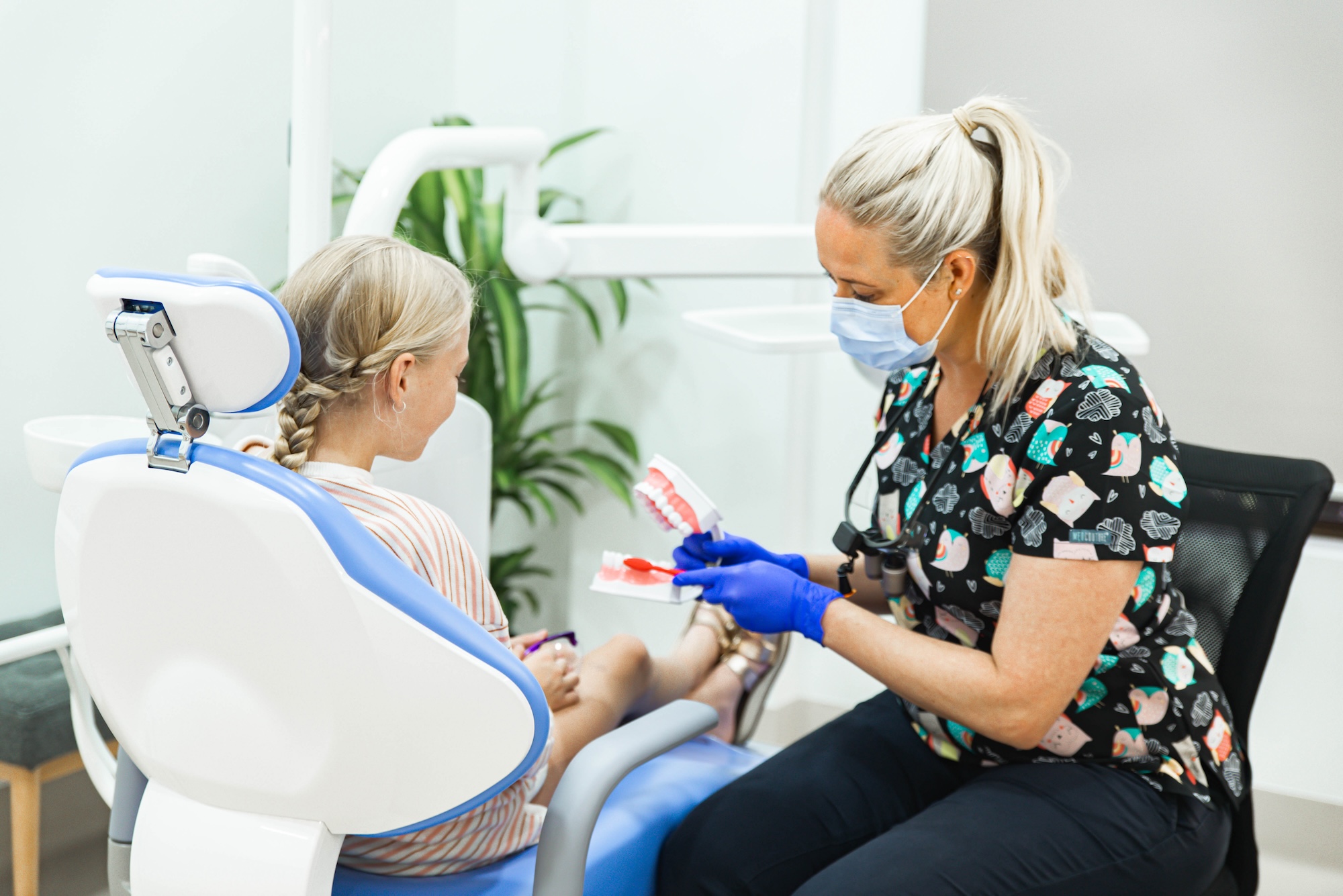 A practitioner at Admire Dentistry uses a dental model to demonstrate oral muscle habits and jaw health to a young patient.