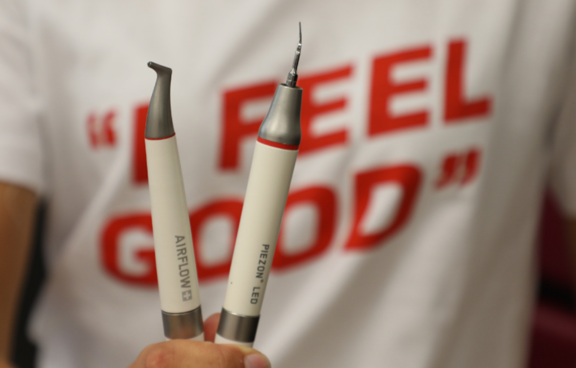 Hand holding Airflow and Piezo dental cleaning instruments. 