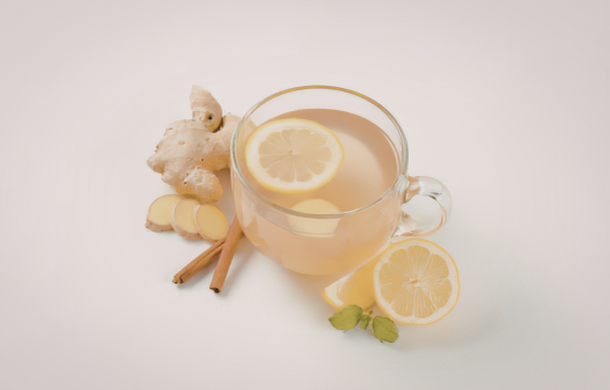 Glass mug of warm lemon and ginger tea with fresh lemon slices. 