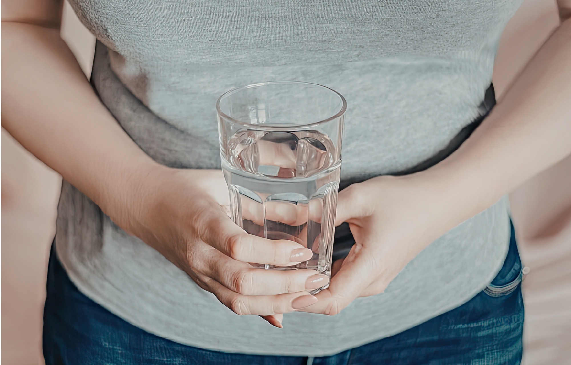 Person holding a clear glass of drinking water. 