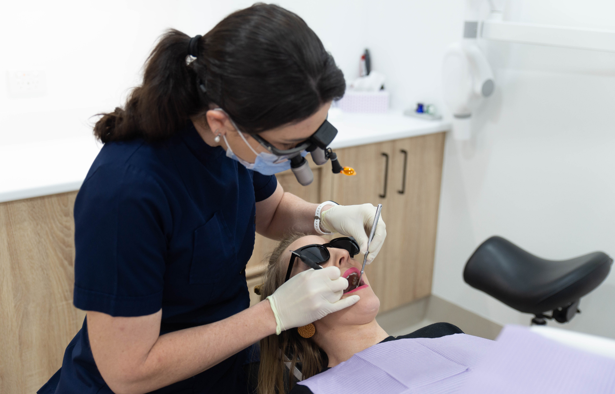 Dentist performing a dental examination on a patient in a clinic chair. 